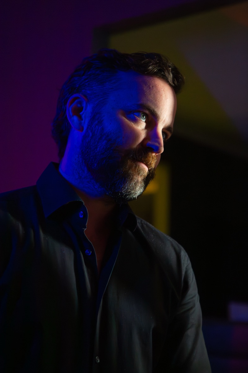 Robert Wilson Smith, actor, in profile in low blue and magenta light, wearing a dark shirt